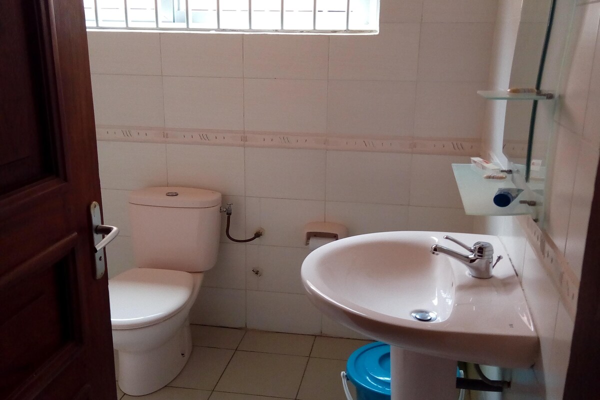 A small, basic bathroom with a toilet, sink, and a window above the toilet.