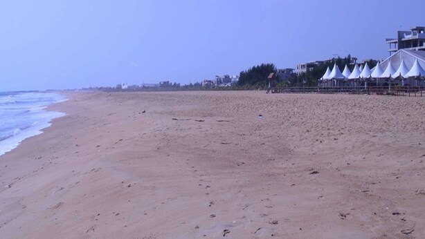 Une plage avec des tentes blanches et des bâtiments en arrière-plan.