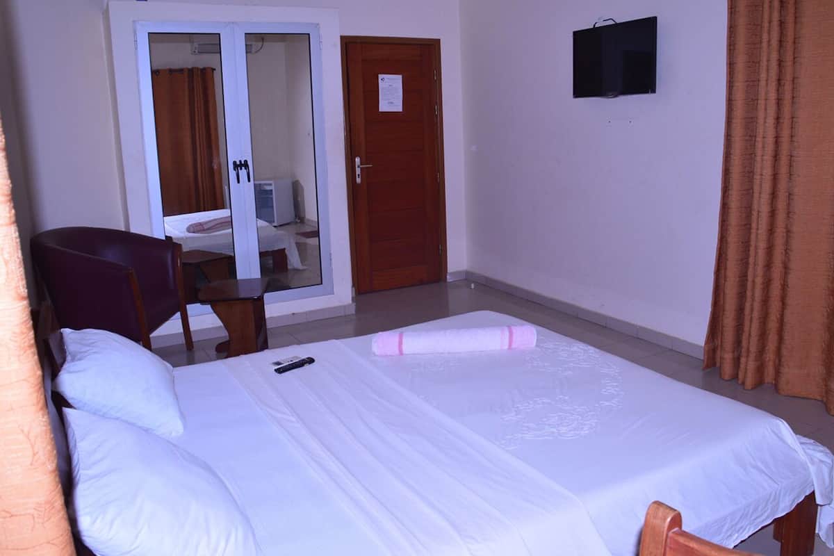 Habitación de hotel con cama, una silla, un escritorio, una puerta y un ventanal pequeño.
