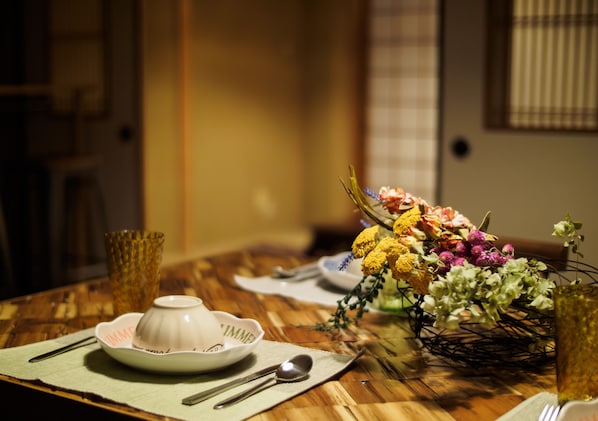 A beautifully set table features a vase with a floral arrangement, a woven basket, and fine dinnerware.