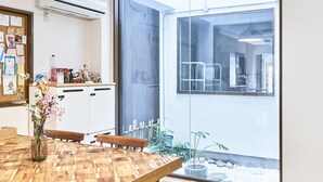 Une cuisine moderne avec des meubles blancs, une table à manger en bois et un luminaire suspendu.