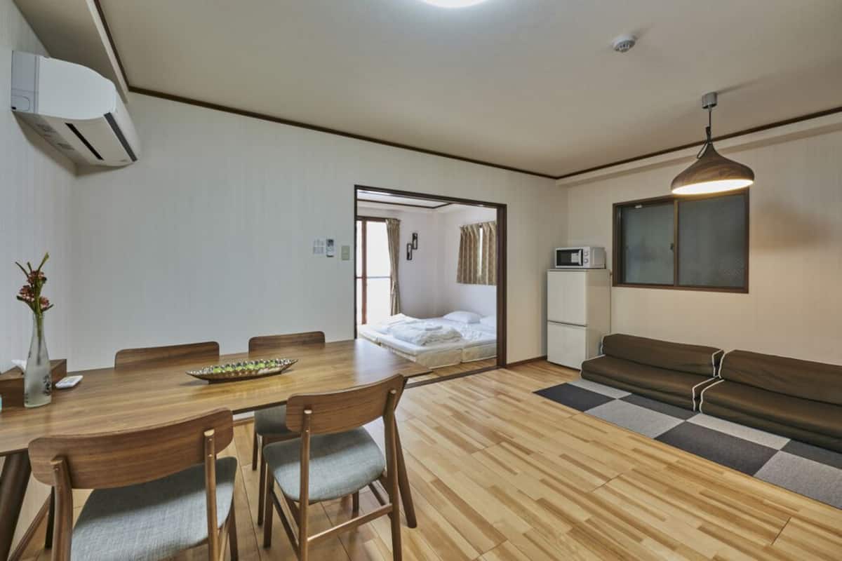 Une pièce de taille modeste comprenant une table à manger en bois, des chaises, un canapé, un lit et un coin cuisine.