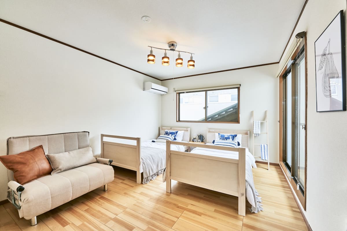 Une chambre moderne avec un canapé, un lit doté d’une tête de lit, une fenêtre et un luminaire au plafond.