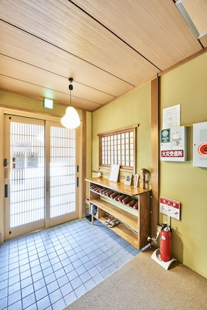 Experience the serene atmosphere of our lobby, featuring a traditional Japanese aesthetic with a wooden ceiling, tiled floor, and warm reception desk.