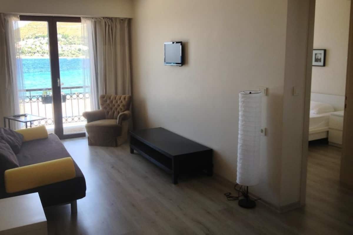 A modern living room with a sofa, a small table, and a TV mounted on the wall.