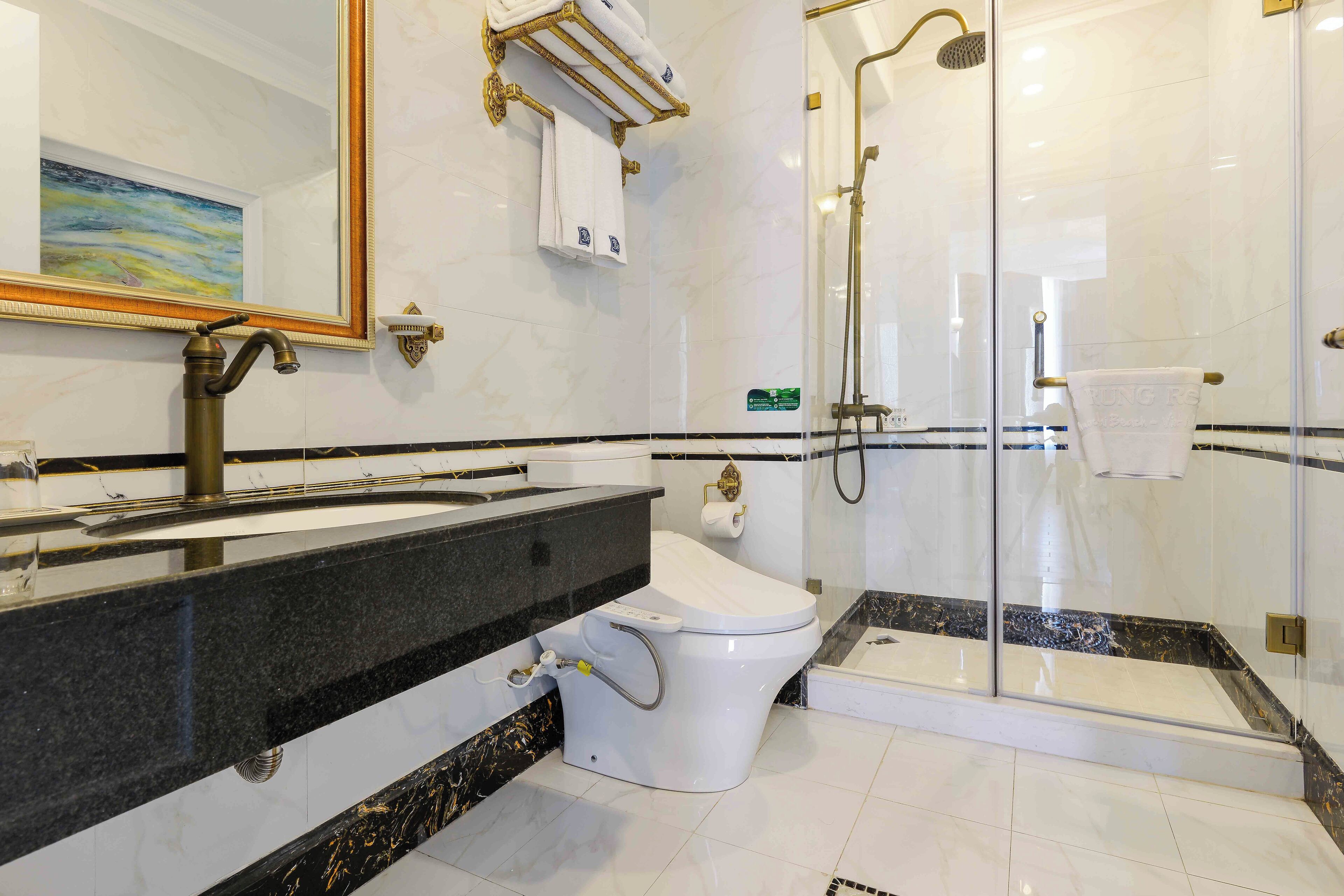 Een moderne badkamer met een marmeren wastafel, een toilet en een douche met glazen wanden.