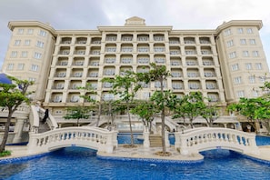 Hotel de diverses plantes amb piscina i un pont.