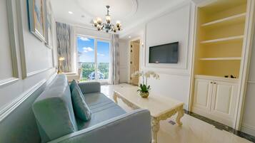 A modern living room with a sofa, a TV mounted on the wall, and a balcony with a view.