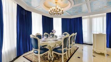 Un comedor formal con una mesa redonda dispuesta para seis personas, rodeada de sillas tapizadas en azul.