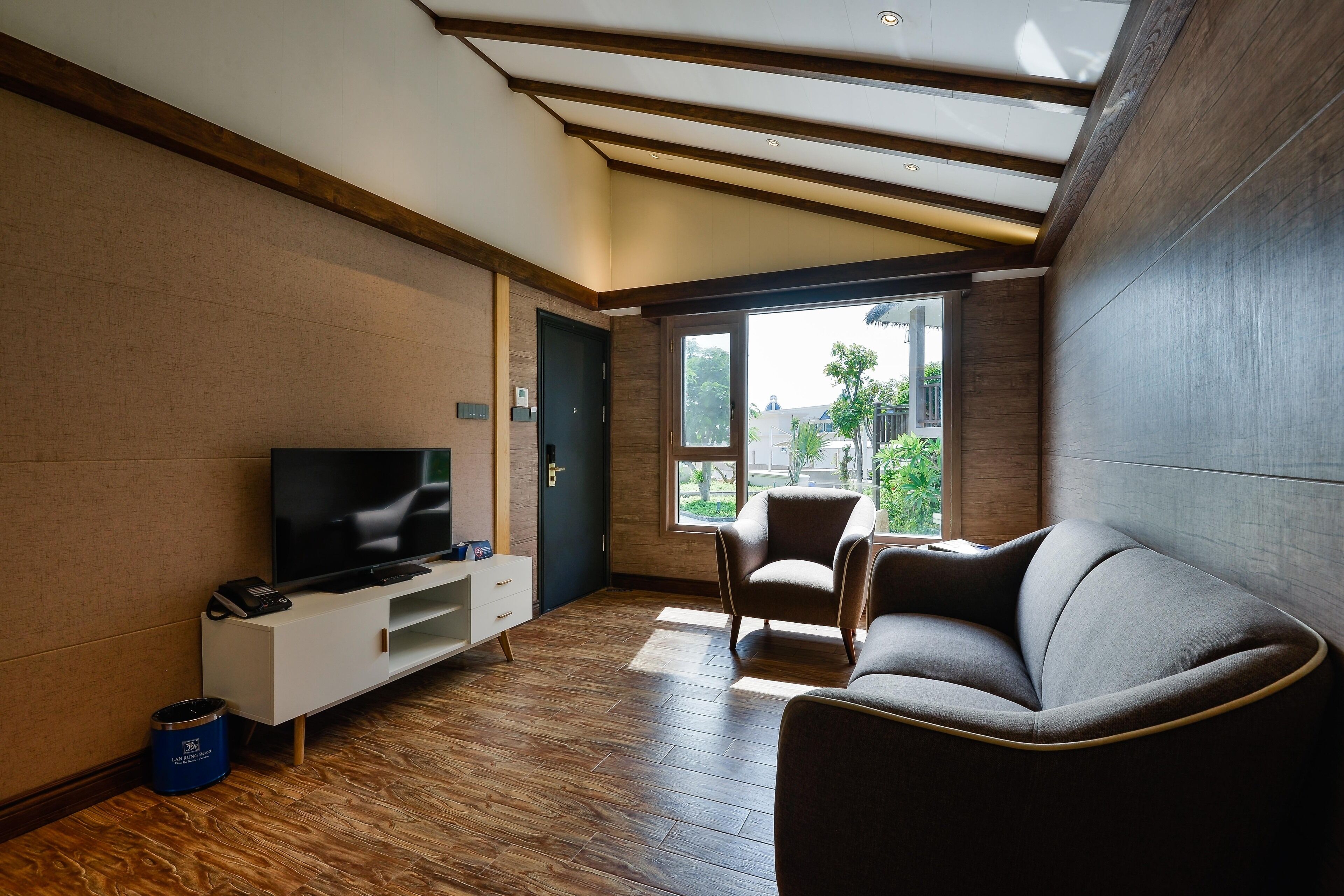 Ein modernes Wohnzimmer mit Fernseher, einer Couch und einem Sessel.