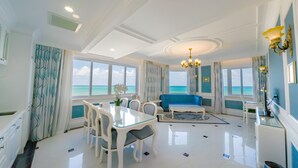 A spacious room with a dining area, a blue sofa, and a view of the sea. - Lan Rung Beach Resort (Ho Chi Minh City)