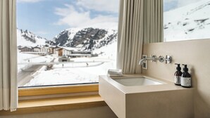 Un baño con vista a un paisaje nevado de montañas.
