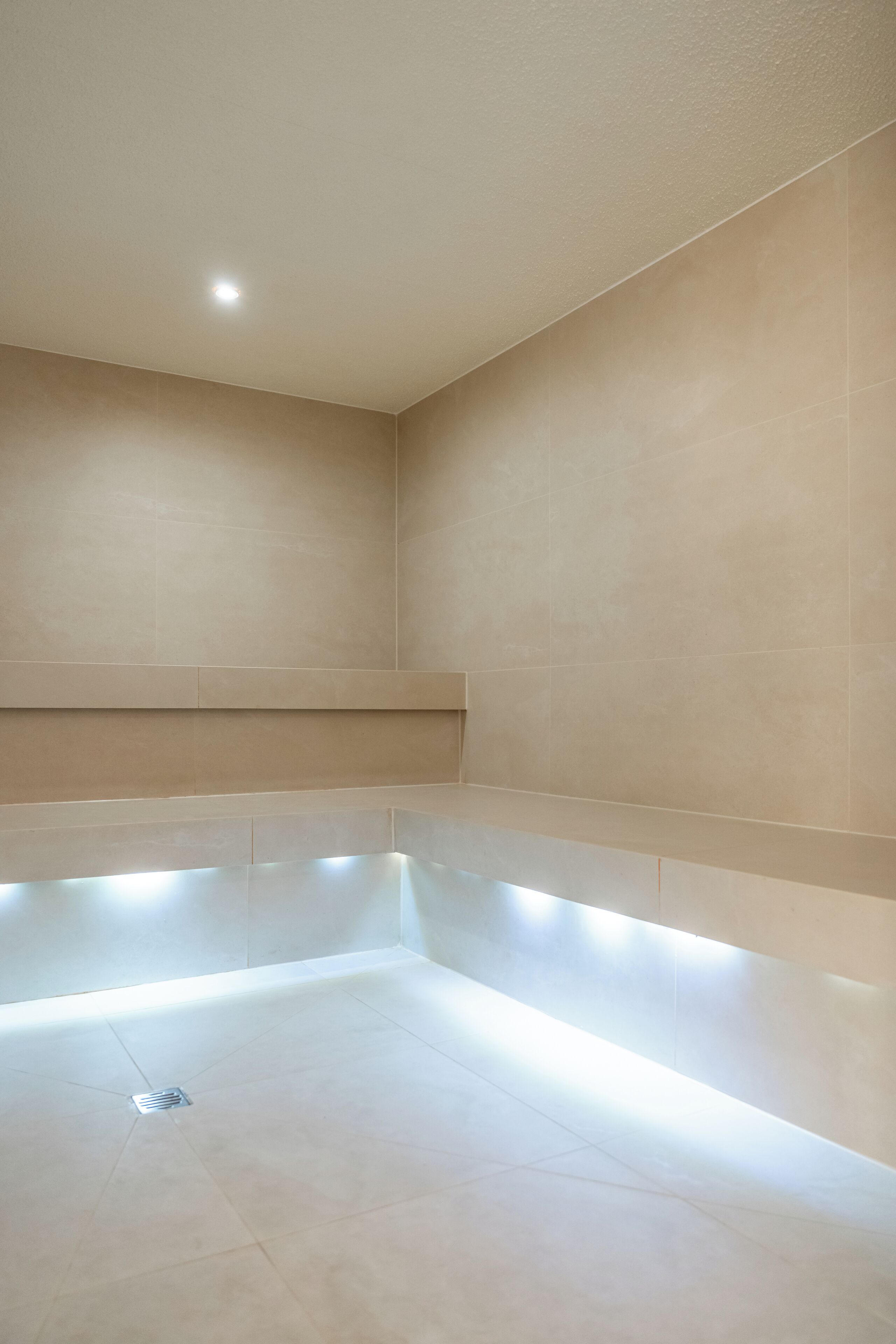 Une salle de bain moderne avec une grande baignoire, un éclairage encastré et un sol carrelé.