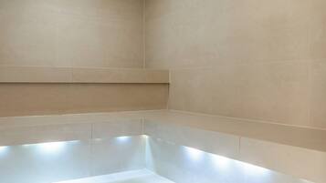 Une salle de bain moderne avec une grande baignoire, un éclairage encastré et un sol carrelé.