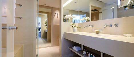 A modern bathroom with a glass shower enclosure, a large mirror, and a vanity with a sink and storage shelves.