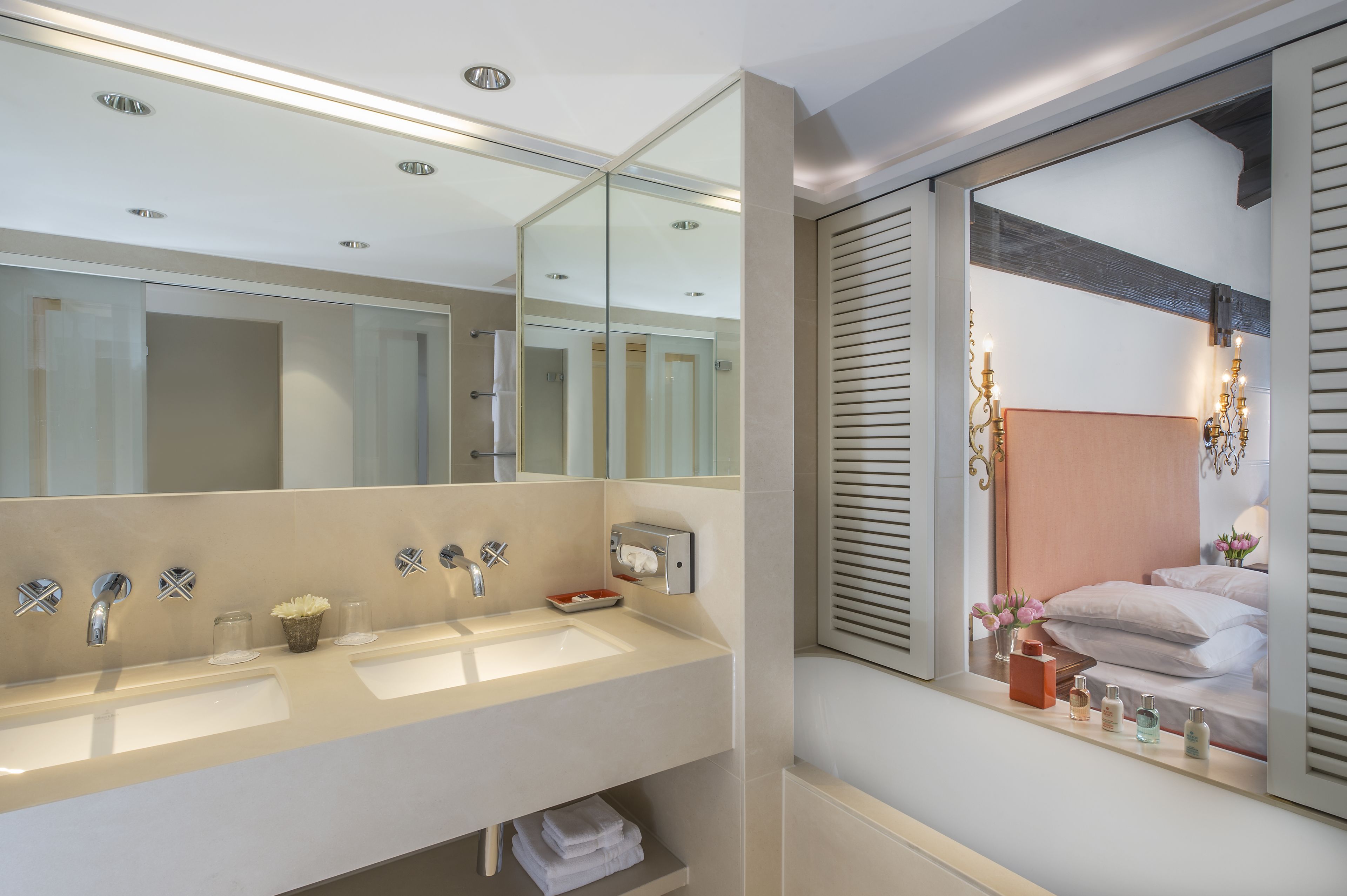 Une salle de bain moderne dotée d’un grand miroir, de deux vasques et d’un meuble-lavabo avec des articles de toilette.