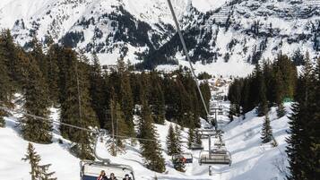 A ski lift with skiers descending a snowy mountain slope.