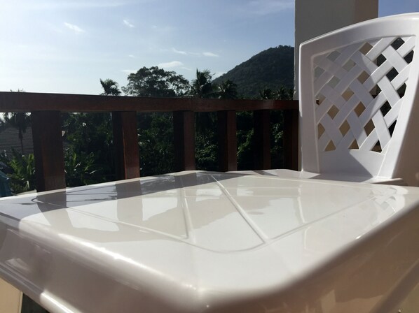 Una silla blanca de plástico con respaldo de celosía en un balcón.