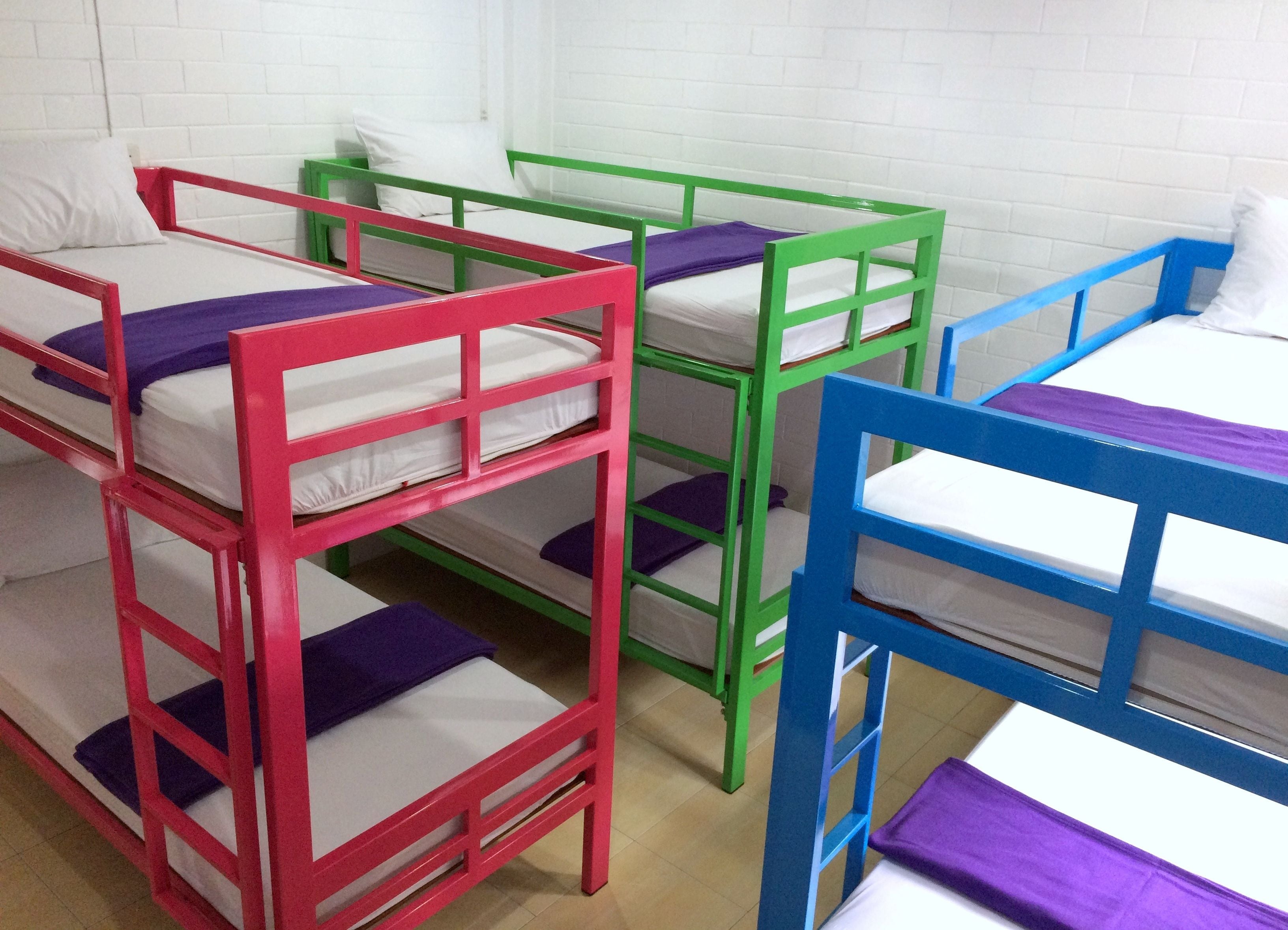 Bunk beds with white mattresses and purple pillows in a room with white brick walls.