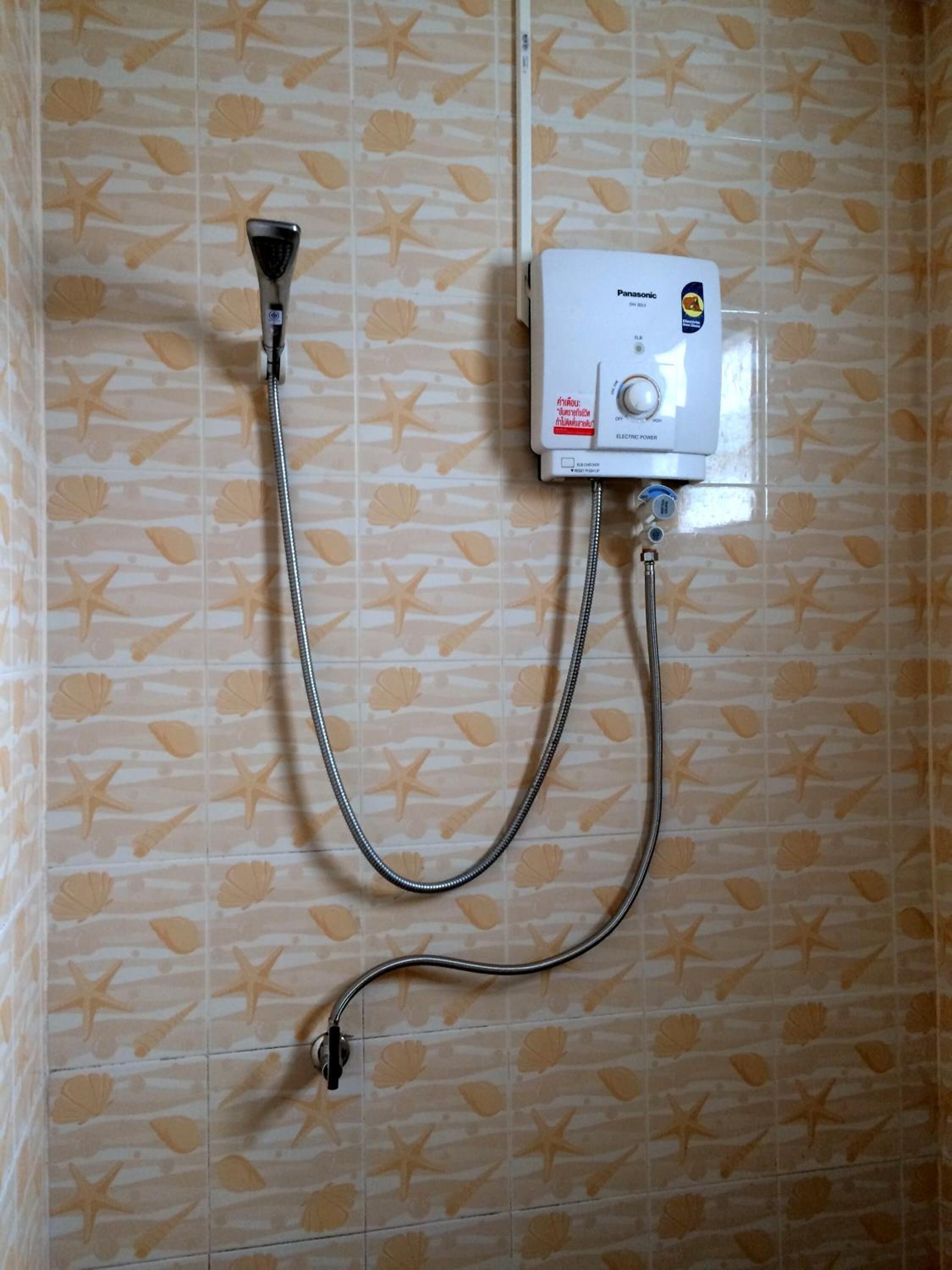 Een badkamer met een in de muur gemonteerde doucheunit, een handdouche en een bedieningspaneel.