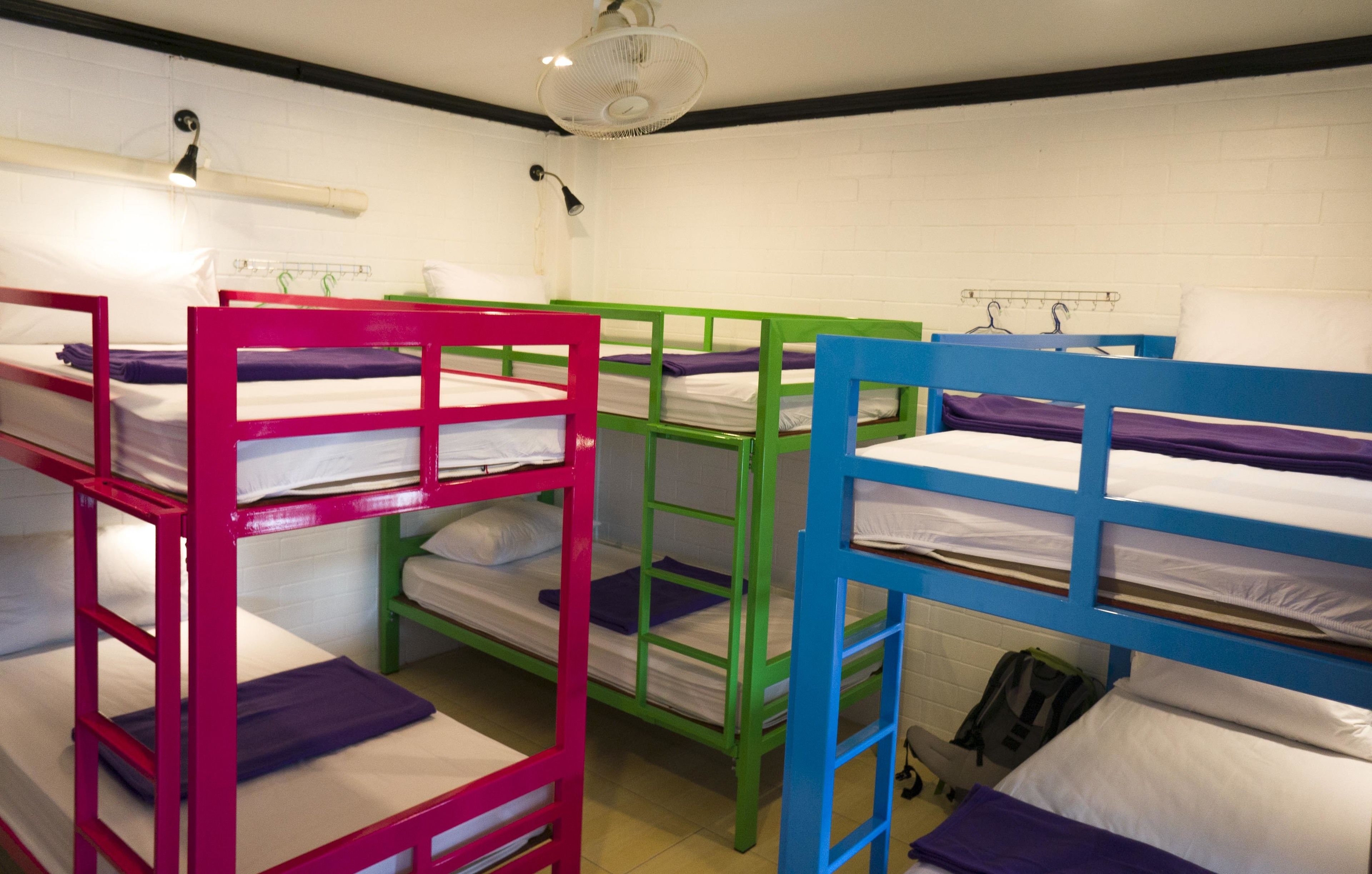 Bunk beds in a dormitory room with white walls and a ceiling fan.