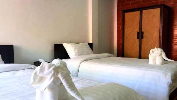 Quarto de hotel com duas camas, cada uma com roupa de cama e toalhas em formato de elefante.