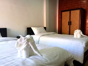 Habitación de hotel con dos camas, cada una con ropa de cama y toallas con forma de elefantes.