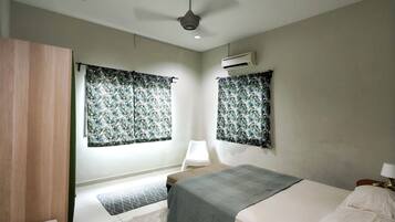 A bedroom with a bed, a nightstand, a lamp, an air conditioning unit, and a ceiling fan.