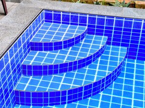 Ein Schwimmbad mit blauen Fliesen und einem gewölbten Design.