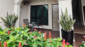 A covered outdoor area with a table and chairs, potted plants, and a staircase leading inside. - Villa 223 (Bandar Baru Bangi)