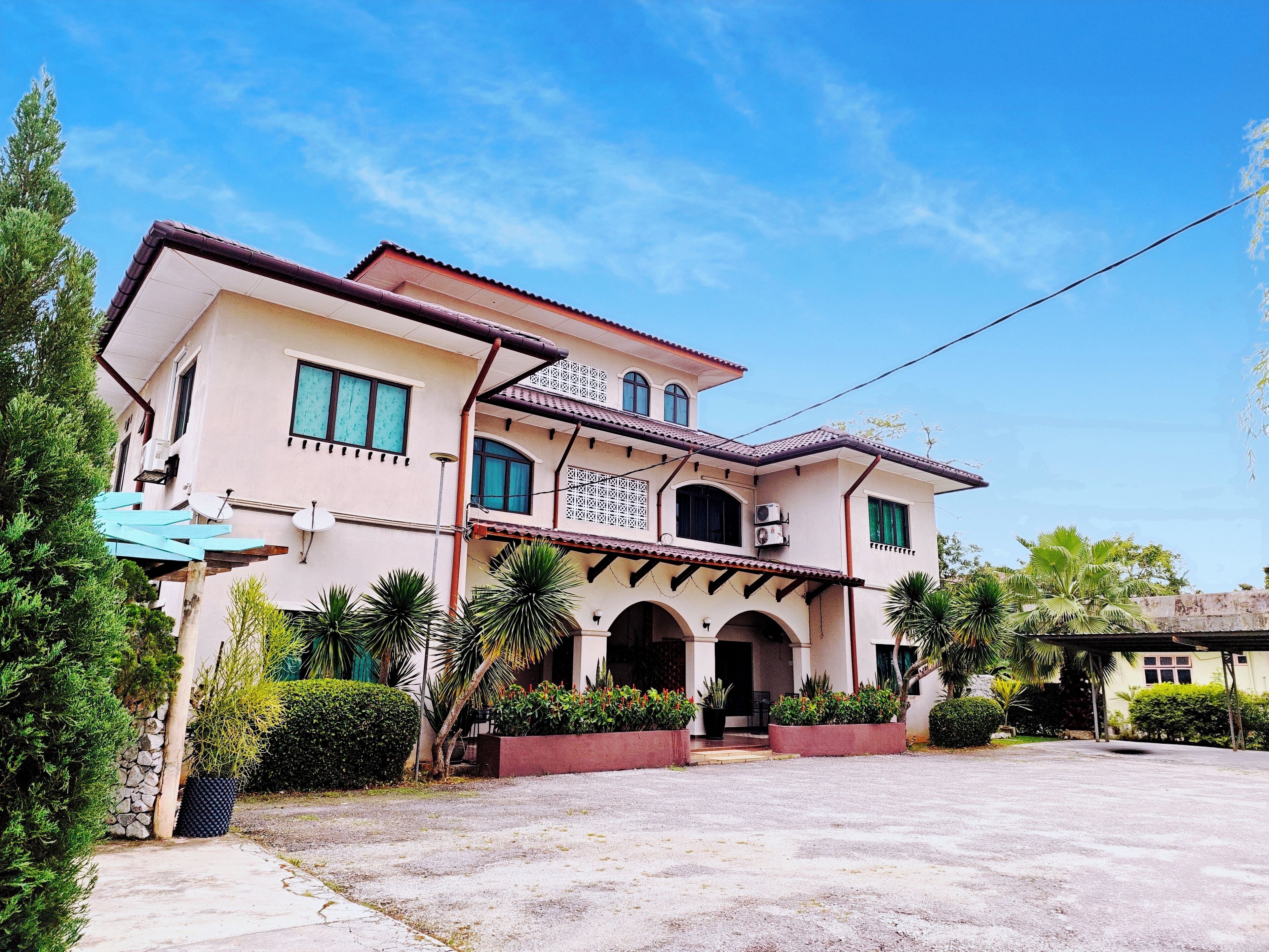 A two-story house with a tiled roof, multiple windows, and a covered entrance with arches.