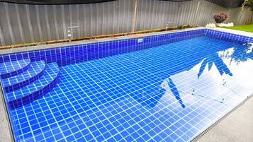 Une piscine aux carreaux bleus, avec une clôture en métal en arrière-plan.