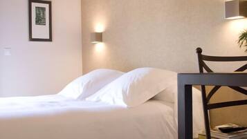A bedroom with a bed, a chair, and a wall-mounted light fixture.