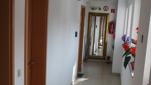 A narrow hallway with tiled flooring, wooden doors, and a green mat at the entrance. - Am Kamin (Duisburg)