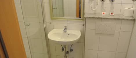 A bathroom with a white sink, a mirror, a toilet, and a shower.