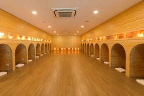 A sauna room with wooden walls and benches, a central heating element, and a wooden floor.