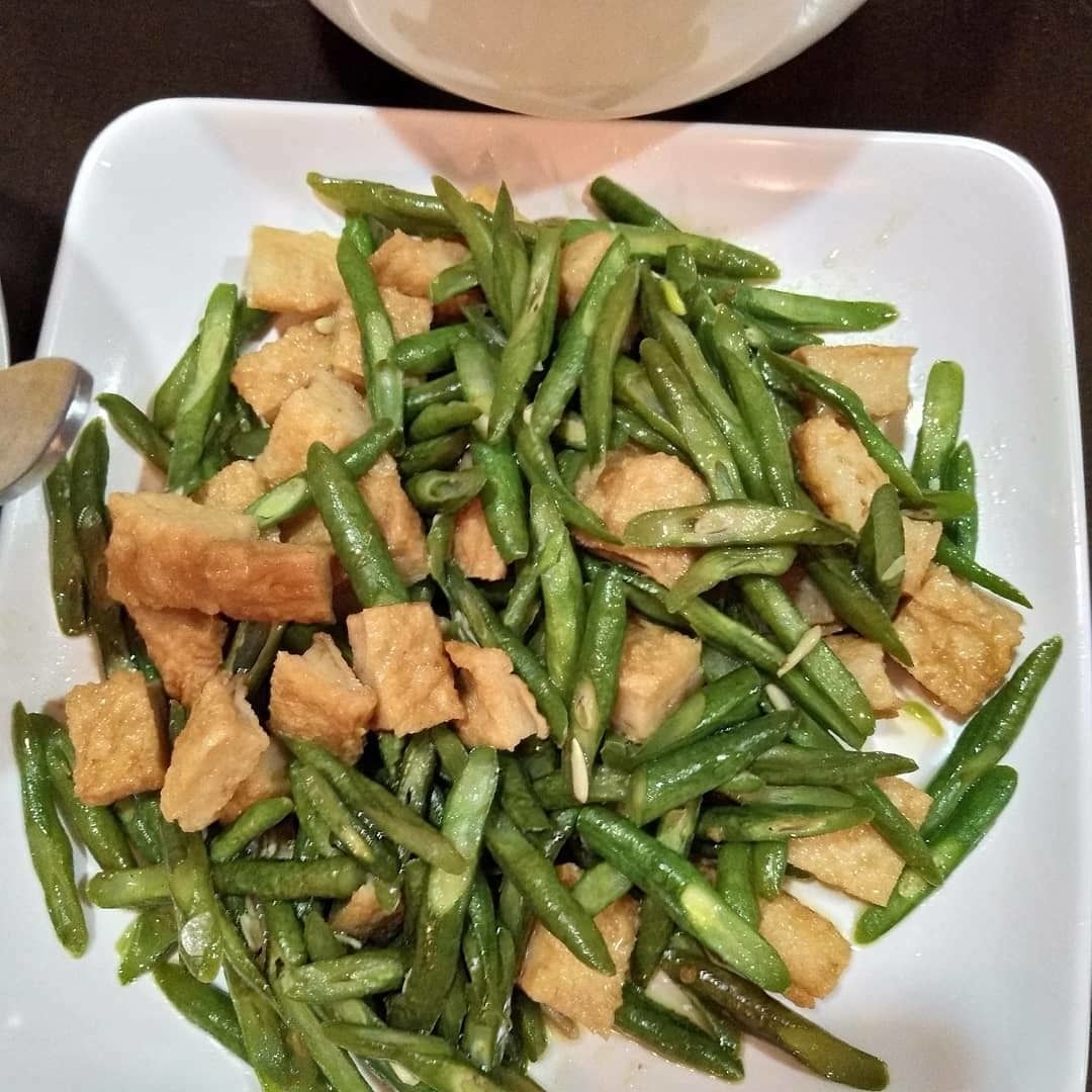 A white plate with green beans and tofu pieces.