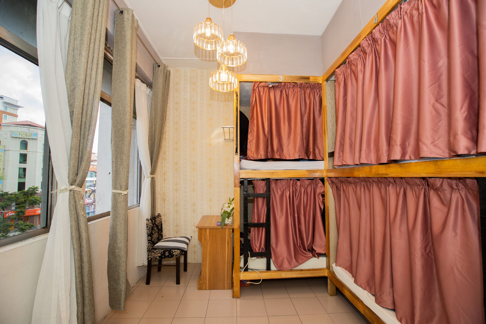 A dorm-style room with bunk beds, a small desk, and a chair.