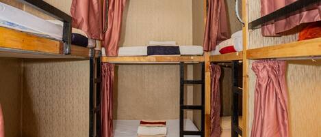 A dormitory room with bunk beds, a ceiling light, and a tiled floor.
