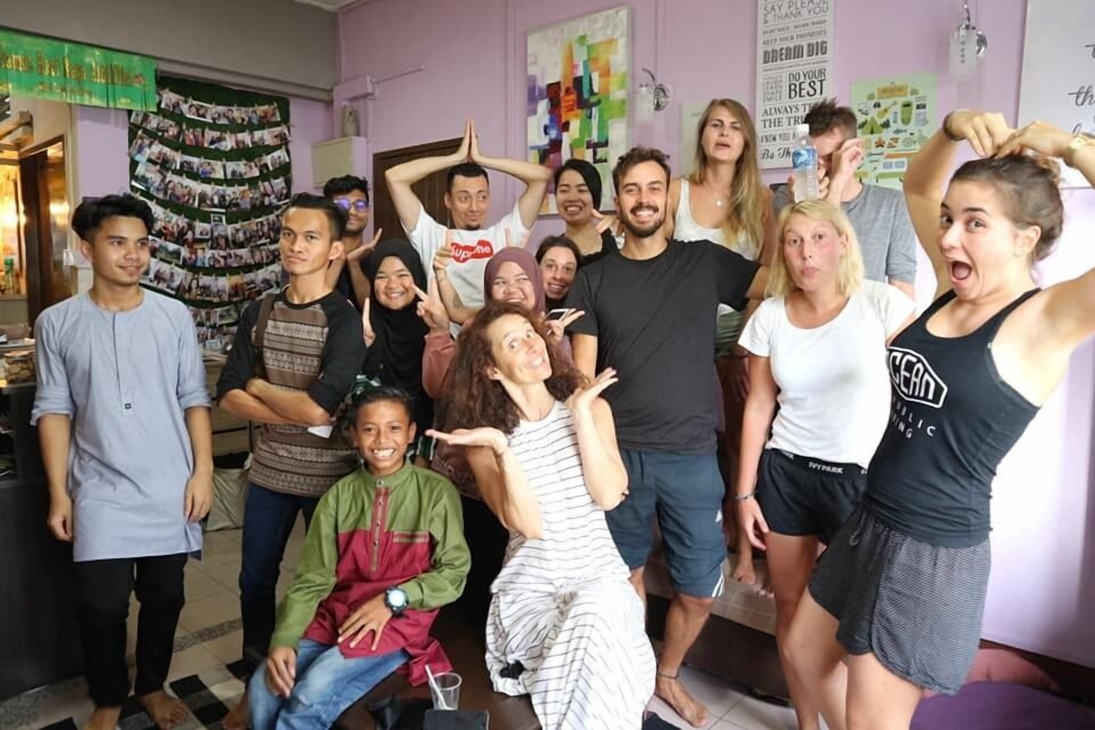 A group of people in a room with a wall decorated with photos and a poster.