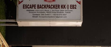 A sign for Escape Backpacker KK at EB2 with contact details and an address.