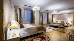 Um quarto de hotel espaçoso com uma cama grande, mesa de cabeceira, escrivaninha e lustre.