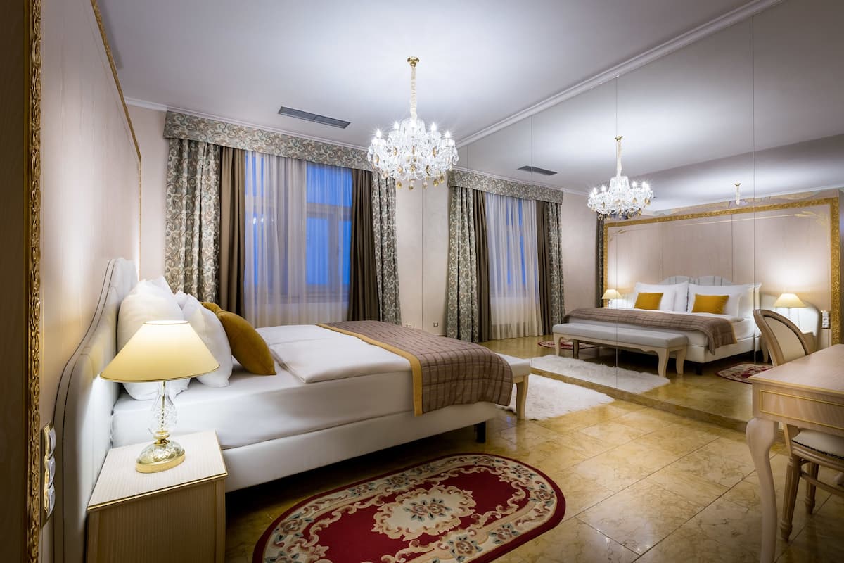 Un'ampia camera d'albergo con un letto grande, un comodino, una scrivania e un lampadario.