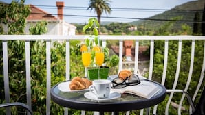 Un balcón con una mesa dispuesta para el desayuno, incluyendo croissants, una taza y un libro.
