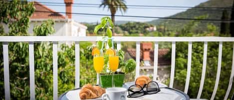A balcony with a table set for breakfast, including croissants, a cup, and a book.