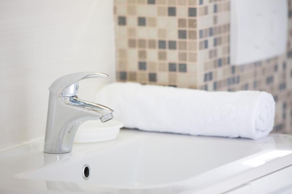 A bathroom with a modern sink, a towel, and a tiled wall.