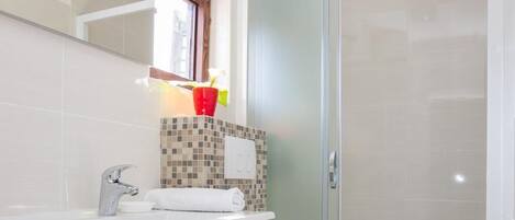 A modern bathroom with a white vanity, a toilet, and a glass shower enclosure.