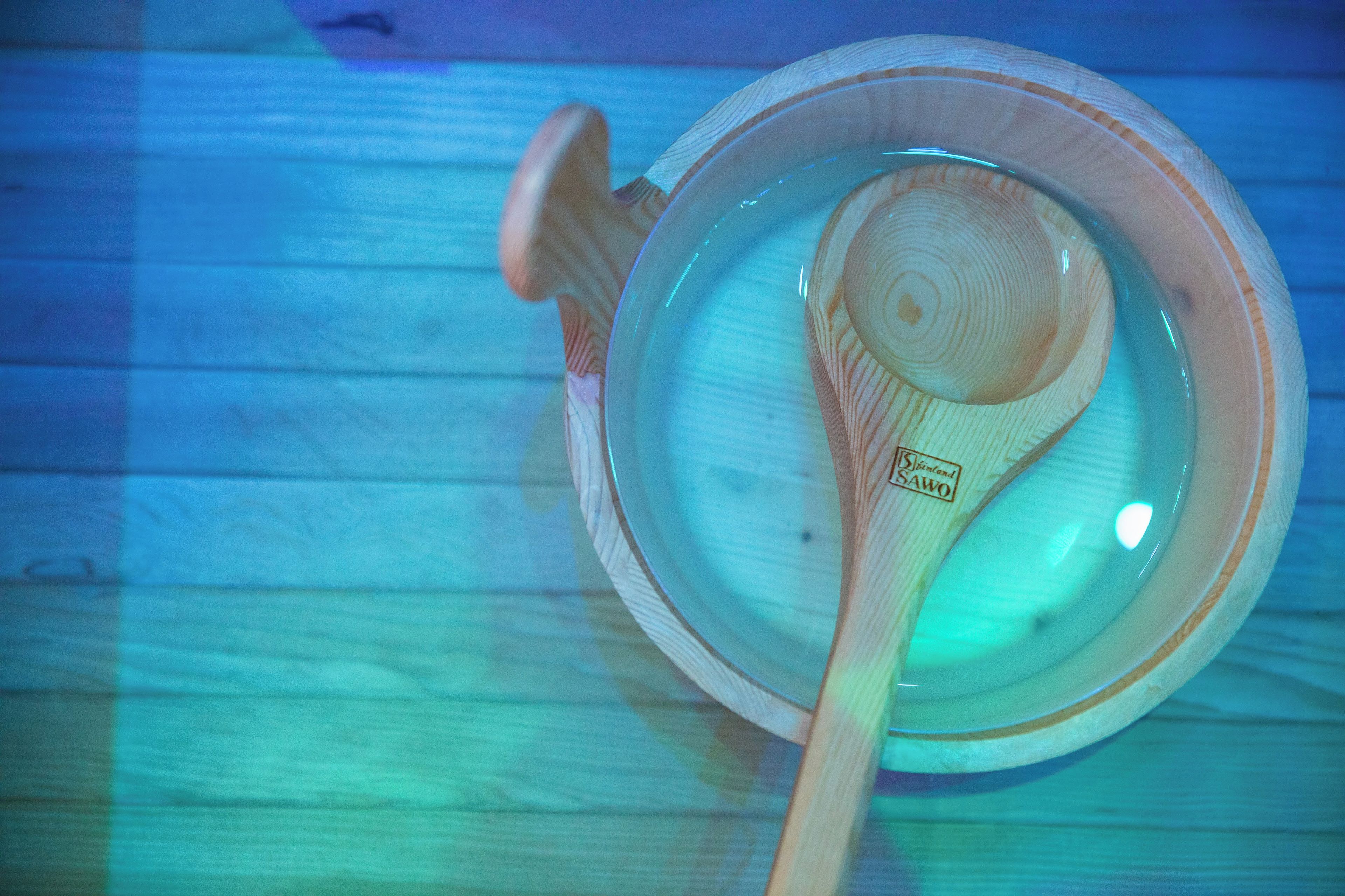 A wooden bowl with a spoon inside, placed on a wooden surface.