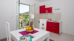 Una pequeña cocina americana con armarios rojos y encimera blanca.