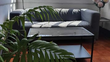 En stue med sofa, sofabord og en potteplante.